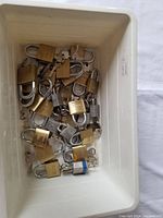 Photo shows a plastic bin containing 25 various padlocks with their keys.