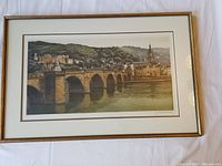 Large framed watercolor print showing Heidelburg cityscape with bridge, signed by artist, displayed flat on white background.