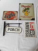 Four metal decorative signs including Best Coffee in Town, Tequila!, Porck hanging sign, and partial Shawn & Ed Brewing Co sign.