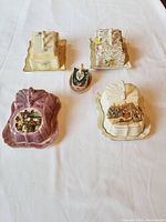 Overview of all 5 vintage butter or cheese dishes with unique lids showing village and cottage designs.