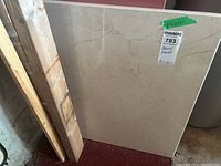 Front view of the beige marble slab standing vertically with visible natural veins and cracks.