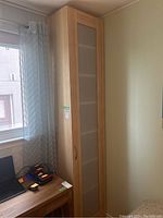 Full exterior view of closed cabinet next to window and desk