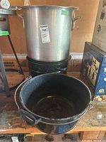 Aluminum and black speckled enamel canning pots stacked on a shelf.