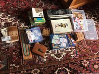 Overview of games laid out including cribbage boards, dominoes sets, card decks, and game boxes on a patterned rug.