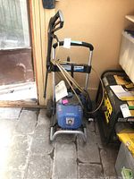 Full view of the blue PowerStroke electric pressure washer with handle and wheels, showing general shape and condition.