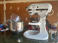 Front view of white KitchenAid mixer with bowl and accessories