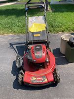 Front view of mower showing deck, handlebar, grass bag.