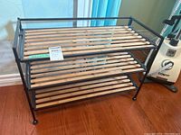 Front view of the steel frame rack with wooden slat shelves, showing three-tier storage with clean wood slats and black metal frame.