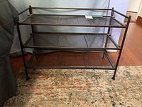 Front view showing three mesh metal shelves, tubular steel frame, and rack dimensions approximately 26.5x12.5x18.5 inches.