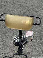 Top view of the desk lamp showing frosted amber rectangular glass shade, black metal frame, and attached power cord with label.