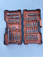 Open driving bit kit case showing all 43 bits and accessories organized in slots with orange and black plastic case.