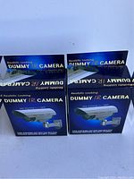 Front view of two boxed dummy IR cameras showing realistic design and flashing red light claim.