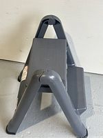 Side view of gray Rubbermaid folding step stool showing textured platform and legs.