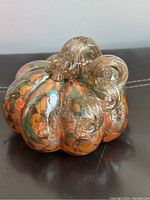 Side angle view showing the multicolor glass segments and textured golden stem of the pumpkin art piece.