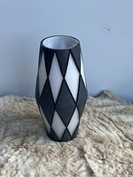 Front view of glass vase showing the black and white diamond geometric pattern and cylindrical tapered shape.