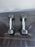 Two Keys 3 lb hex dumbbells side by side on a dark surface, showing hexagonal shape and weight marking.