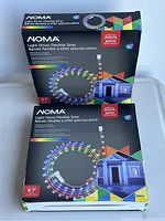 Two boxed NOMA Light Show Flexible Strips, multi-coloured LED lights showing size and package graphics.