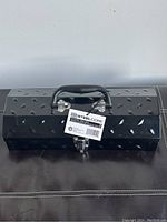 Front view of black Steel Core steel toolbox with handle and label tag visible