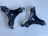 Top view of two black steel tri-dollies showing rubber pads on each corner.