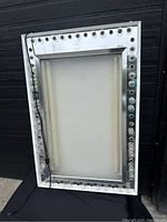 Front view of rectangular LED wall art mirror with aluminum frame showing circular light sockets around the perimeter with some lamps missing.