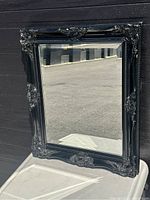 Full view of the rectangular wall mirror with black wood ornate frame showing its overall condition and design details.