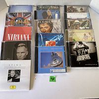 Top view showing all 15 CDs with cover art from multiple rock and pop artists, arranged in rows.