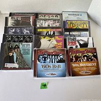 Photo of 15 music CDs neatly arranged featuring Rolling Stones, Jimi Hendrix, and Woodstock themed albums and compilations.