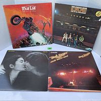 Four vintage vinyl album covers: Meat Loaf's 'Bat Out of Hell', The Guess Who 'Live at the Paramount', John Lennon's 'Double Fantasy', and Bob Seger's 'Night Moves', arranged two standing and two lying flat.