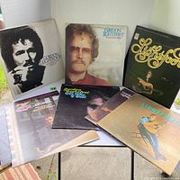 Full view of the 8 vintage Gordon Lightfoot vinyl albums arranged on a glass surface. Various album covers with images of Gordon Lightfoot seen, showing condition and artwork.