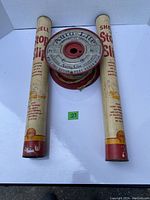 Front view of two Shell Stop Slip tubes with Auto-Lite cable spool centered between them, showing labels and packaging details.
