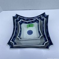Three nested decorative ceramic bowls in blue and white with floral and border designs