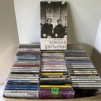 Photo showing the box of approximately 180 used CDs, arranged in rows with Simon & Garfunkel Old Friends box set prominently on top.