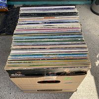 Top-down view of a full cardboard box containing 96 vintage vinyl albums with various colored spines visible.