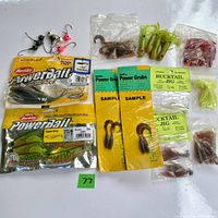 Fishing lures laid out on white background including PowerBait Ripple Shad packages, Bucktail Jig packages, Power Grubs, various small soft plastics and jig heads