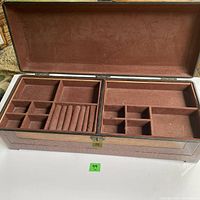 Open jewelry box showing compartment arrangements lined with pink velvet material.