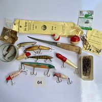 Top-down image of vintage fishing lot items laid out on white surface, showing lures, hooks, bobbers, cutting tool, weights, and fishing line.
