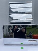 Front view of shiny stainless steel bread box with reflective surface and labeled 'BREAD' plaque.