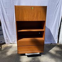 Front view of the teak veneered cupboard with visible door hinges and drawers.