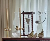 Wide view showing all items including two candlesticks, glass hurricane lamp, hourglass with twisted wood pillars, three porcelain partridges, and glass angel figurine.