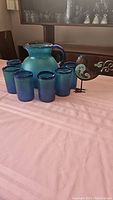 Full set with pitcher, six tumblers, and metal bird on table.