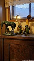 Five Blue Mountain Pottery animal figurines displayed on a wooden surface near a window, including a horse with colt, two ducks, a goose, and another duck in different glazes.