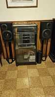 Full stereo system set up showing the stereo cabinet, stacked components inside, and two speakers on stands.