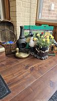 Photo of assorted garden decor items including woven basket, chiminea, duck statue, flower pot and green painted garden stake with animals