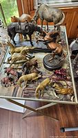 Photo of a variety of horse figurines and sculptures on a table showing different sizes and materials