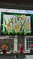 Full view of stained glass hummingbird panel hanging in window showing hummingbirds, yellow flowers, and green leaves.
