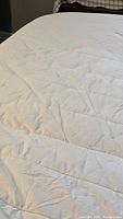 Close-up of white quilted mattress cover surface showing soft fabric and stitching pattern.