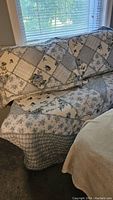 Blue and white floral patchwork quilted comforter and pillow shams on a queen bed, showing the overall pattern and fit.