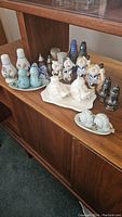 Photo showing a collection of whimsical and vintage salt & pepper shakers arranged on a wooden surface, including white birds, pig characters, glass shakers, and snail sets.