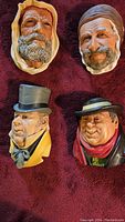 Four vintage Bossons chalkware heads on red fabric background, showing all faces and general condition.