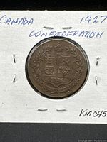 Front side of medallion showing Canadian coat of arms with crown and laurel branches, and inscriptions.